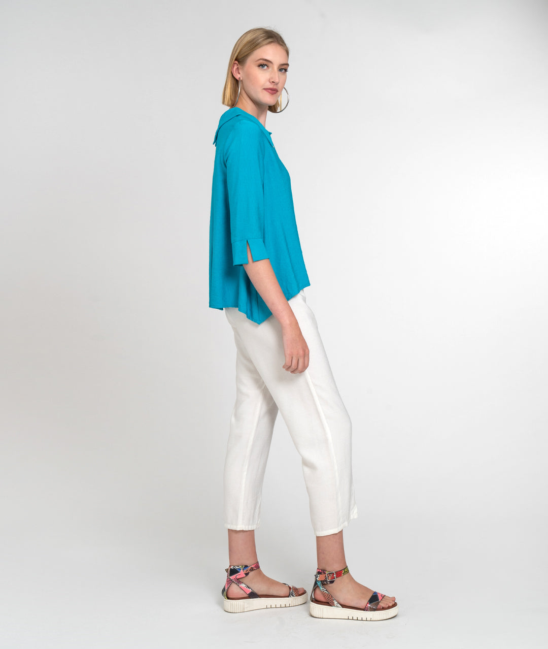 model in a slim white pant with a teal button down blouse