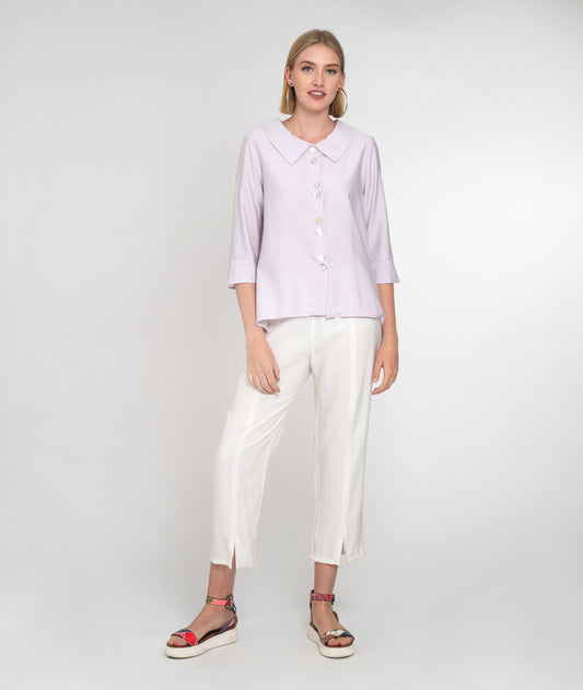 model in a light lilac button down blouse with 3/4 sleeves and a twin button detail. worn with a slim cut white pant with small slits at the ankle