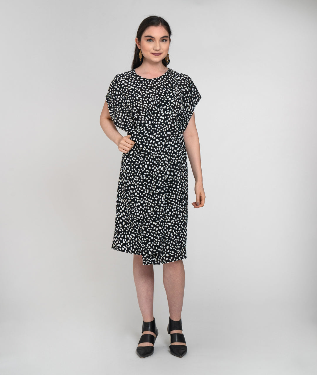 model in a black and white dot print dress with a halter style strap coming from the side panels to around her neck