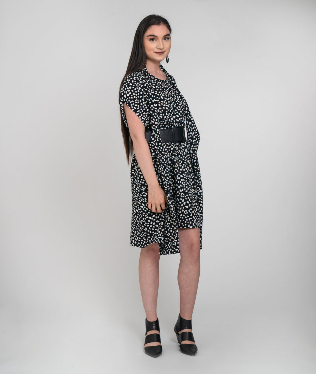 model in a black and white dot print dress with a halter style strap coming from the side panels to around her neck