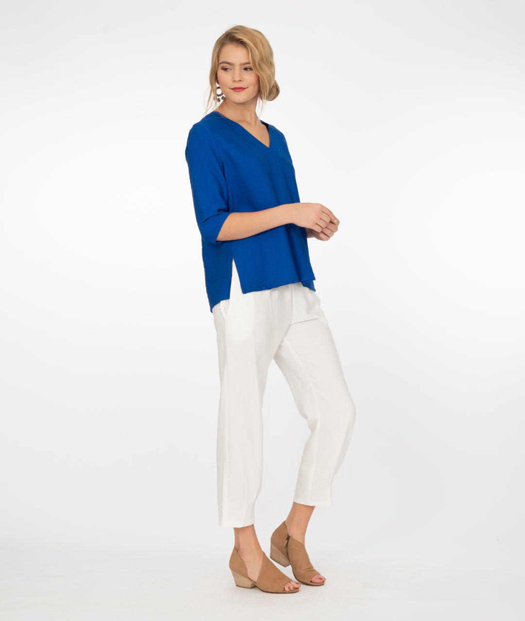 model in a v neck electic blue top with white pants, in front of a white background