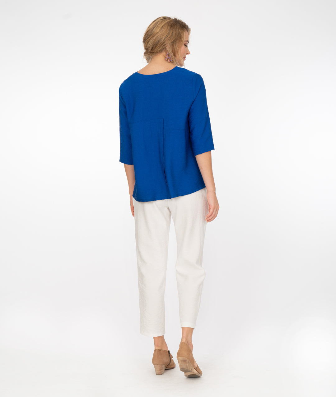 model in a v neck electic blue top with white pants, in front of a white background