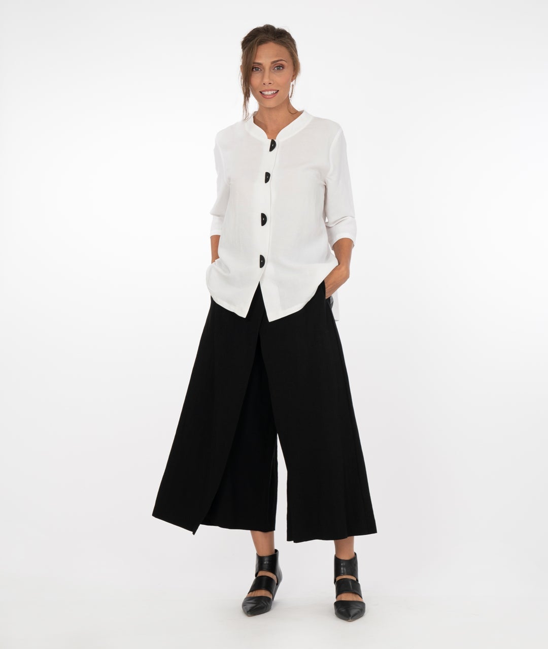 model wearing a white button up top with black pants in front of a white background
