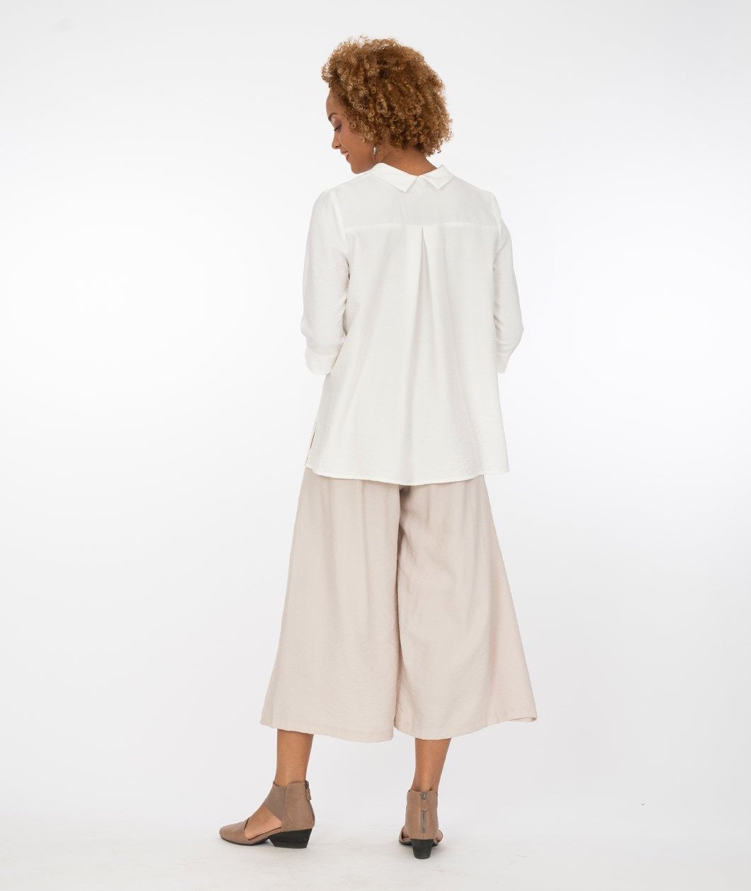 model with a white button up shirt with a wide leg khaki with an overlapping panel in the front on either leg. 