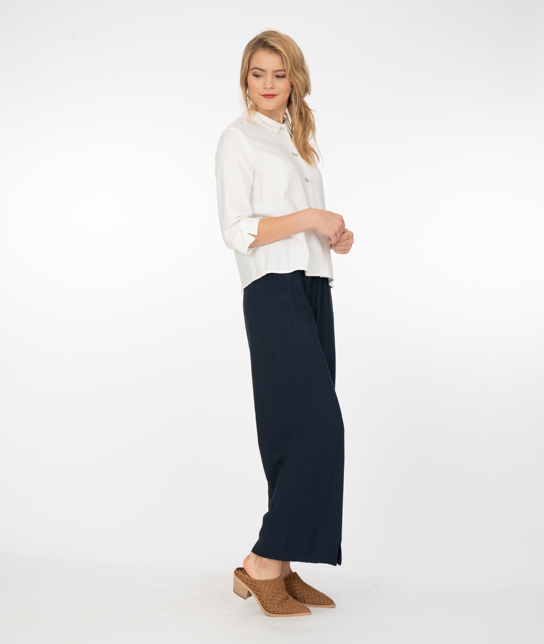model in a white button down blouse with a wide leg blue pant with a center seam and ankle split on either leg