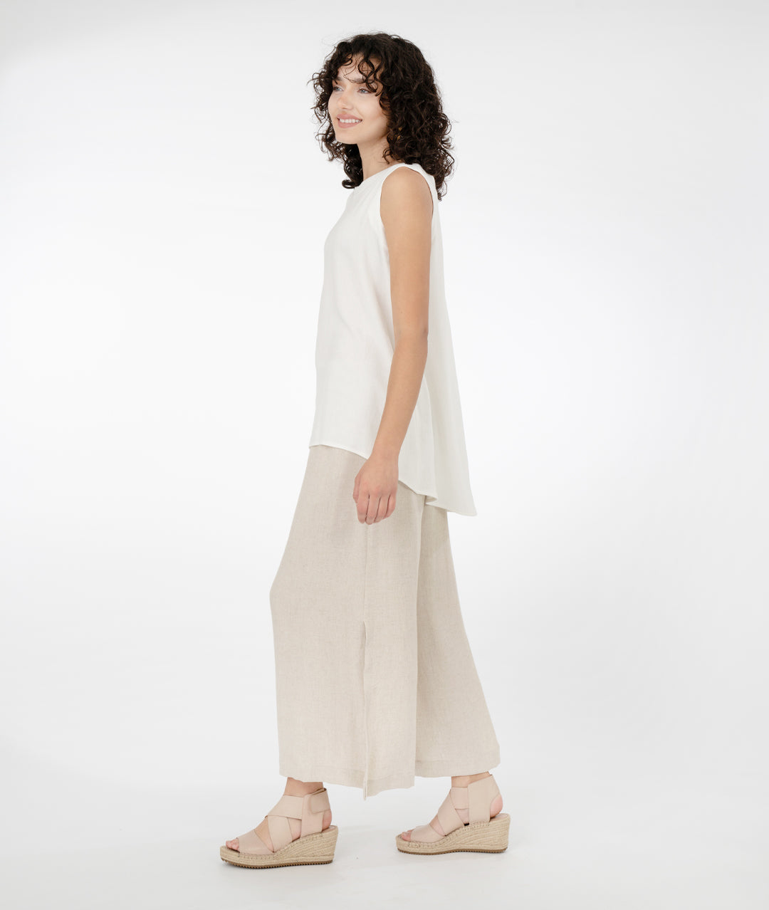 model in a long white pullover tank top with a wide leg oatmeal color pant on a hanger, with large splits on the sides from knee to hem