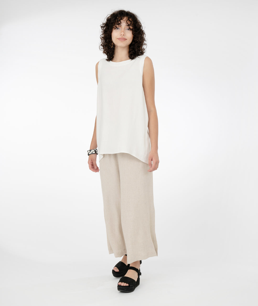 model in a long white pullover tank top with a wide leg oatmeal color pant on a hanger, with large splits on the sides from knee to hem