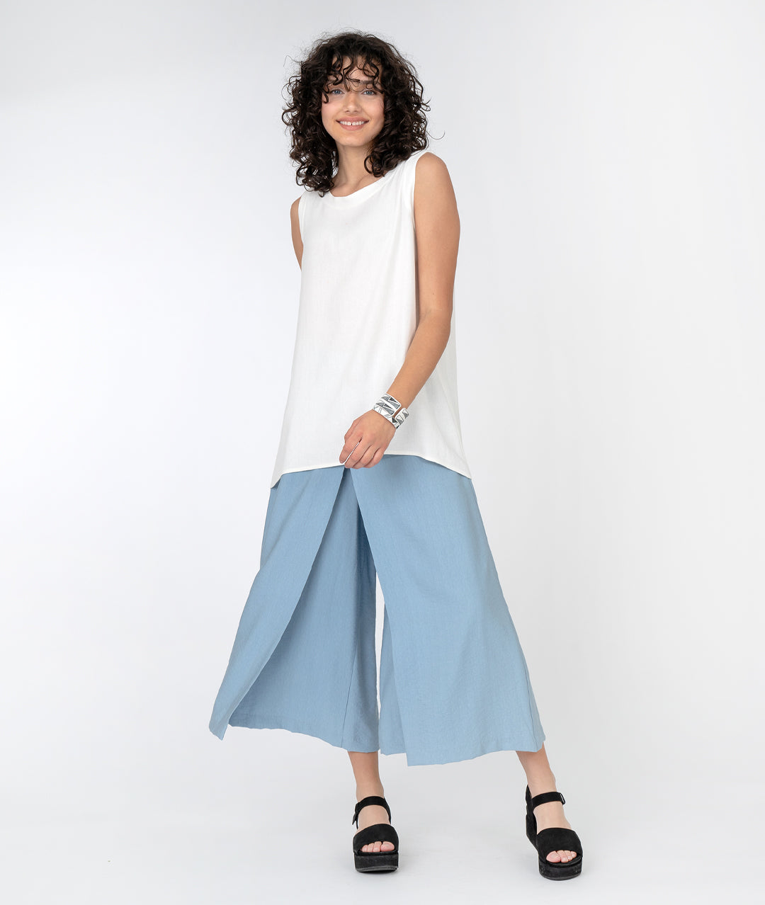 model in a long white tank with a wide leg light blue pant with an overlap panel in the front