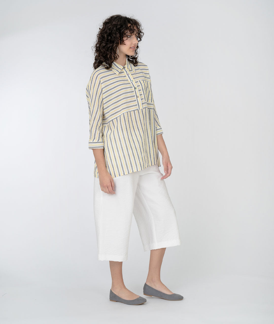 model in a grey, white and yellow striped top with a wide leg cropped white pant