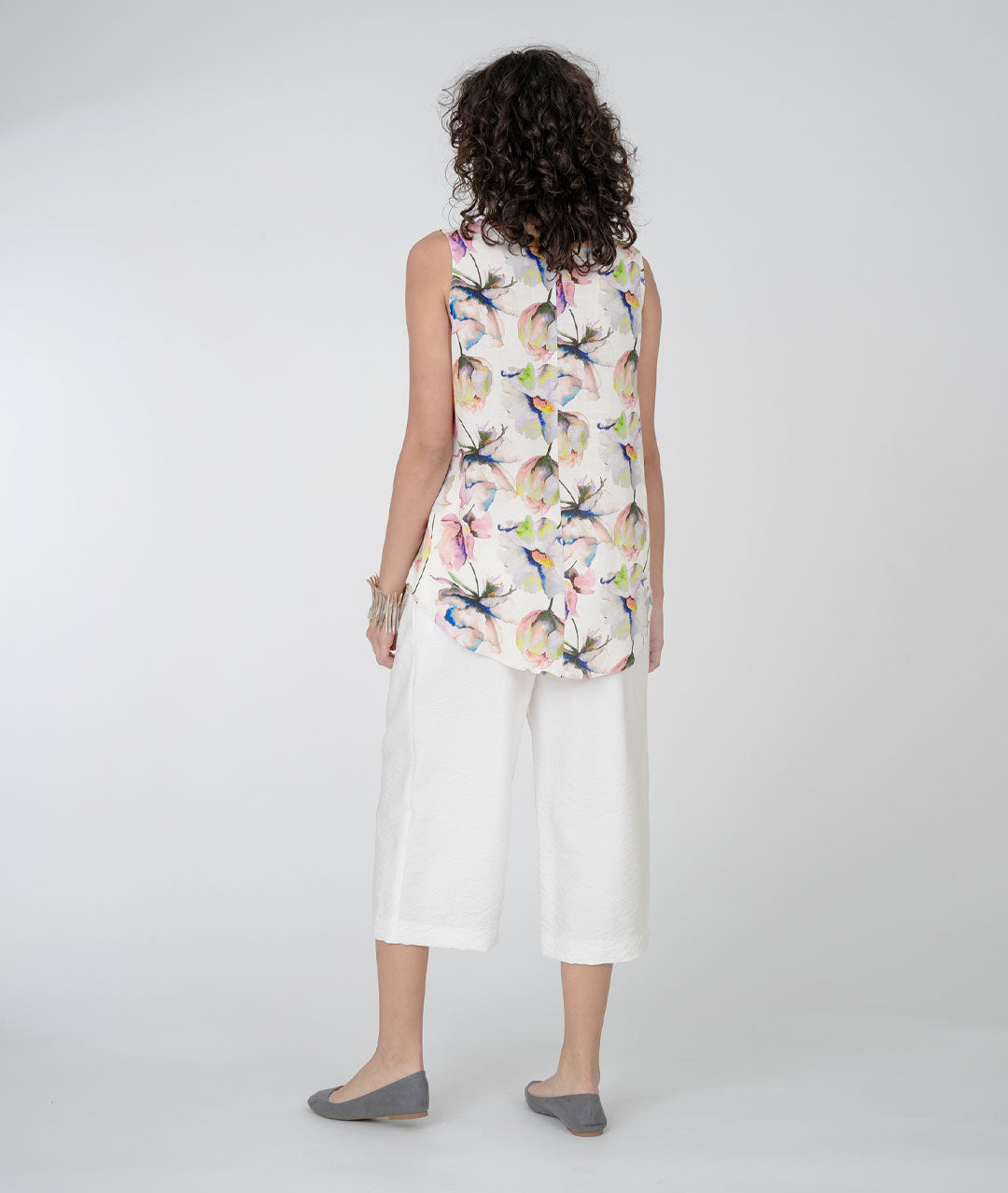model in a white cropped pant with a floral print tank with a white background