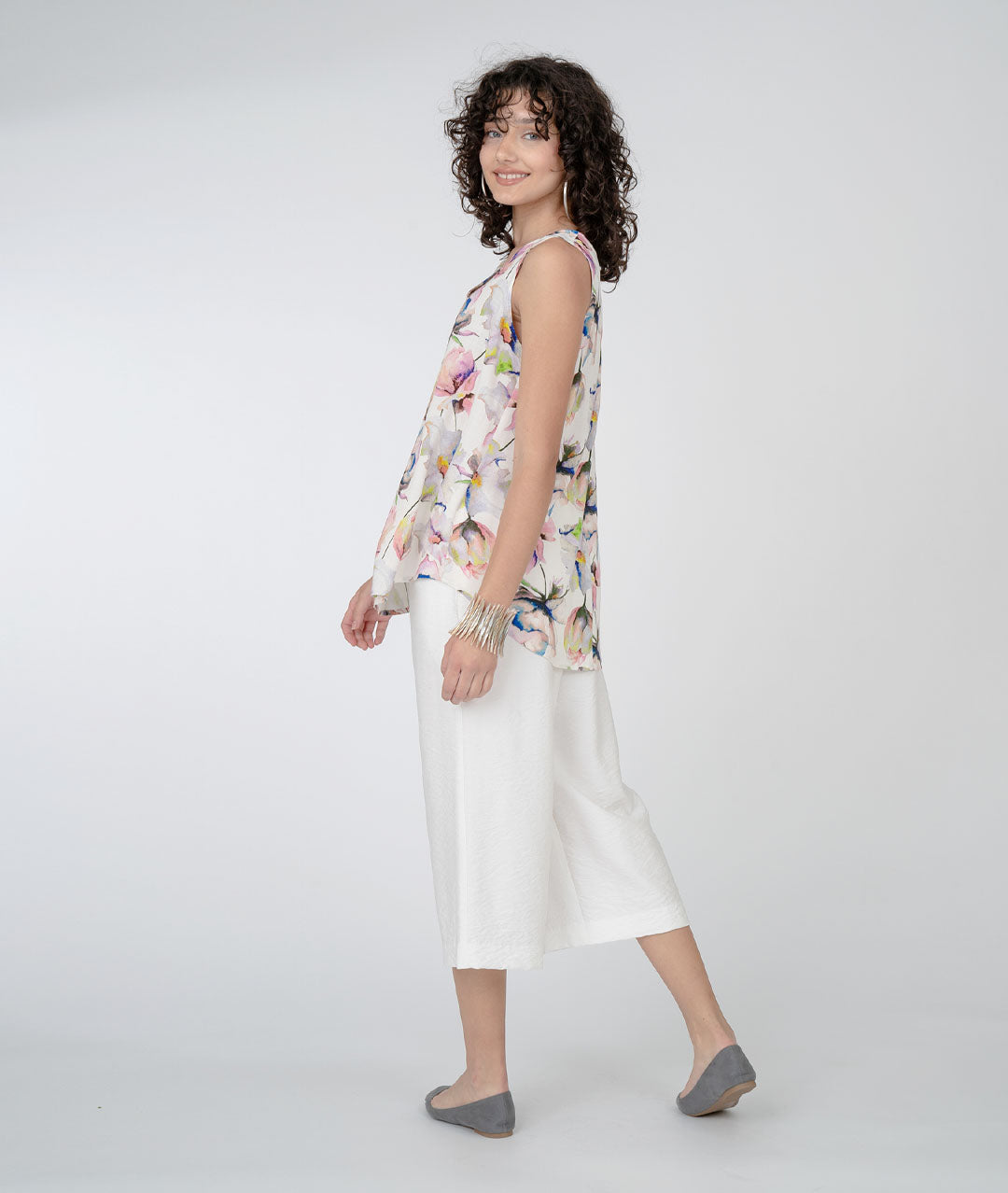 model in a white cropped pant with a floral print tank with a white background