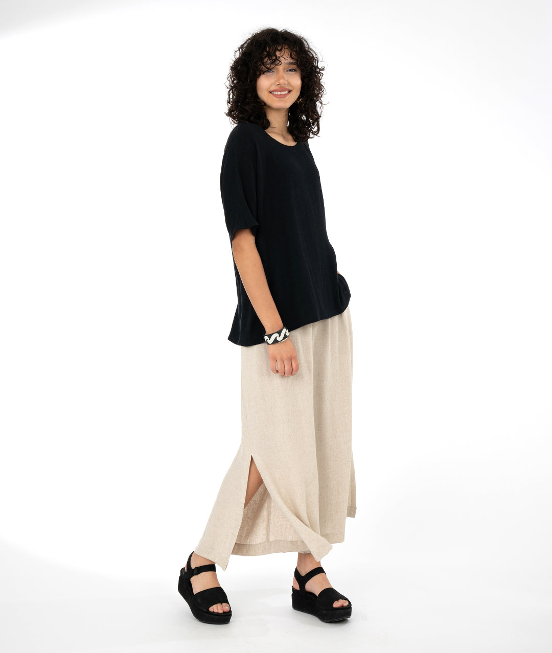 model in a wide leg oatmeal color pant with a split from hem to knee, worn with a long pullover black tee style top