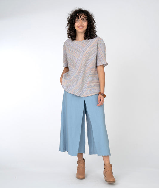 model in a wide leg blue pant with a multicolor stiped top with an asymmetrical panel