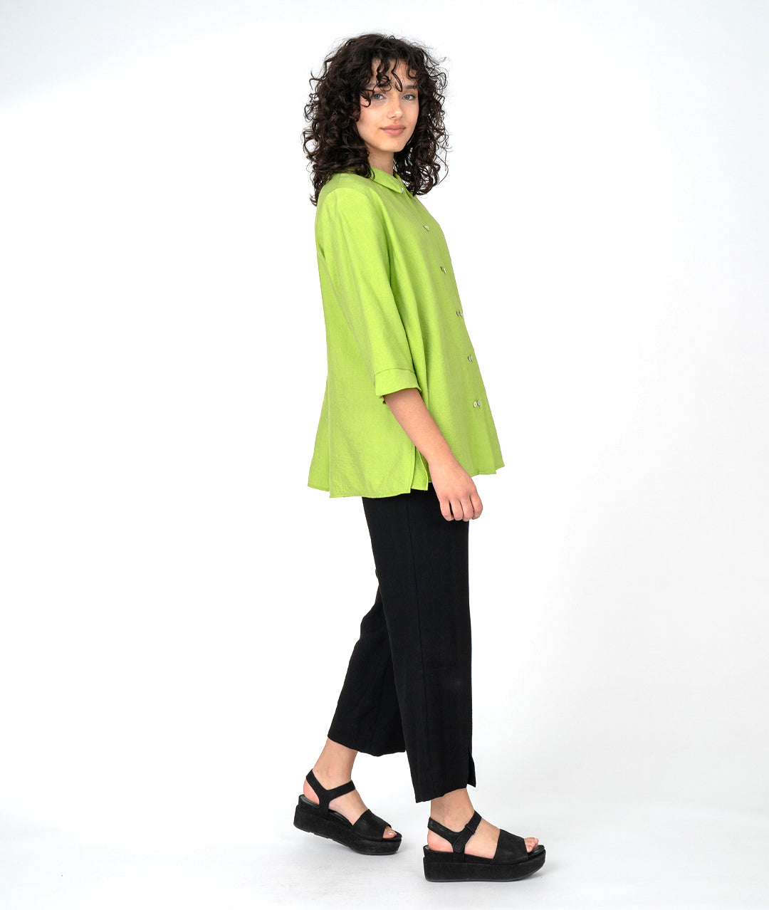 model in a slim black pant, worn with a lime button down blouse with a twinbutton detail, 3/4 sleeves and a long body