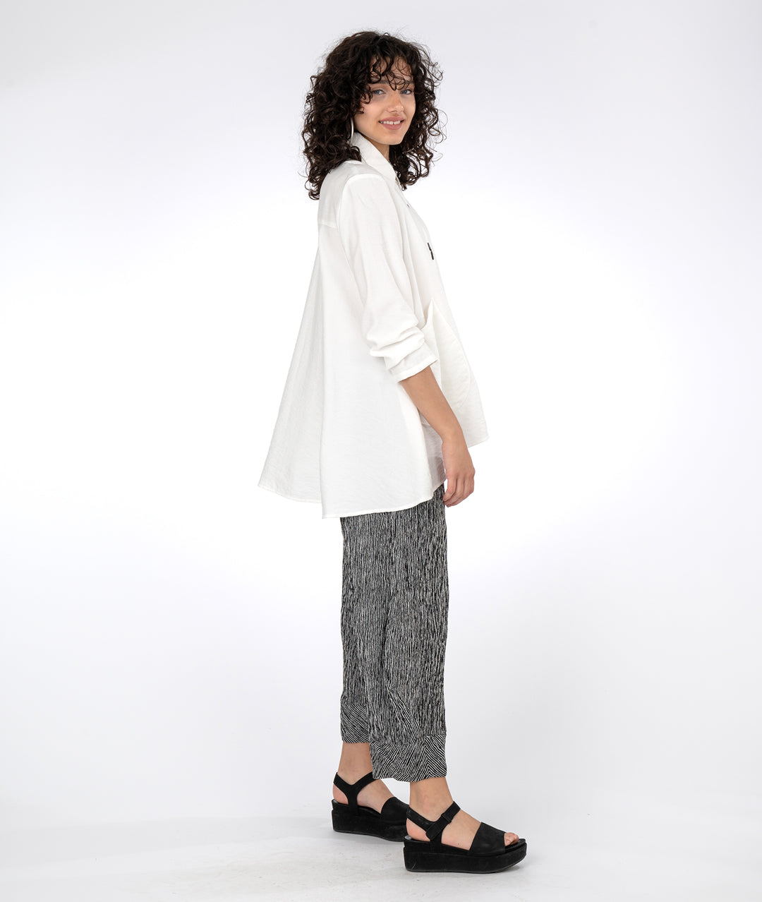 model in a black and white striped pant with a white blouse with a full flowy body and oversized pockets at the hips