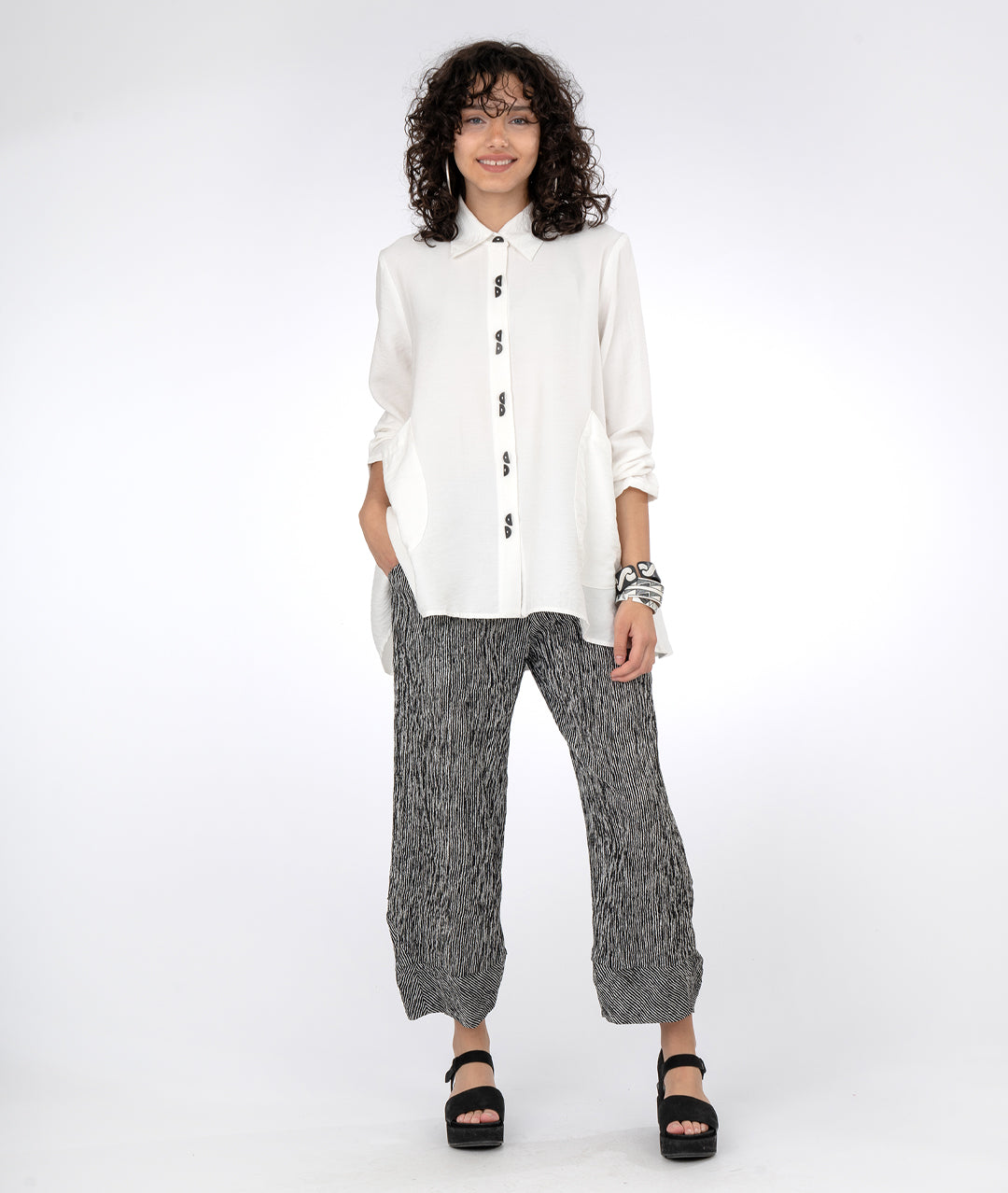 model in a black and white striped pant with a white blouse with a full flowy body and oversized pockets at the hips