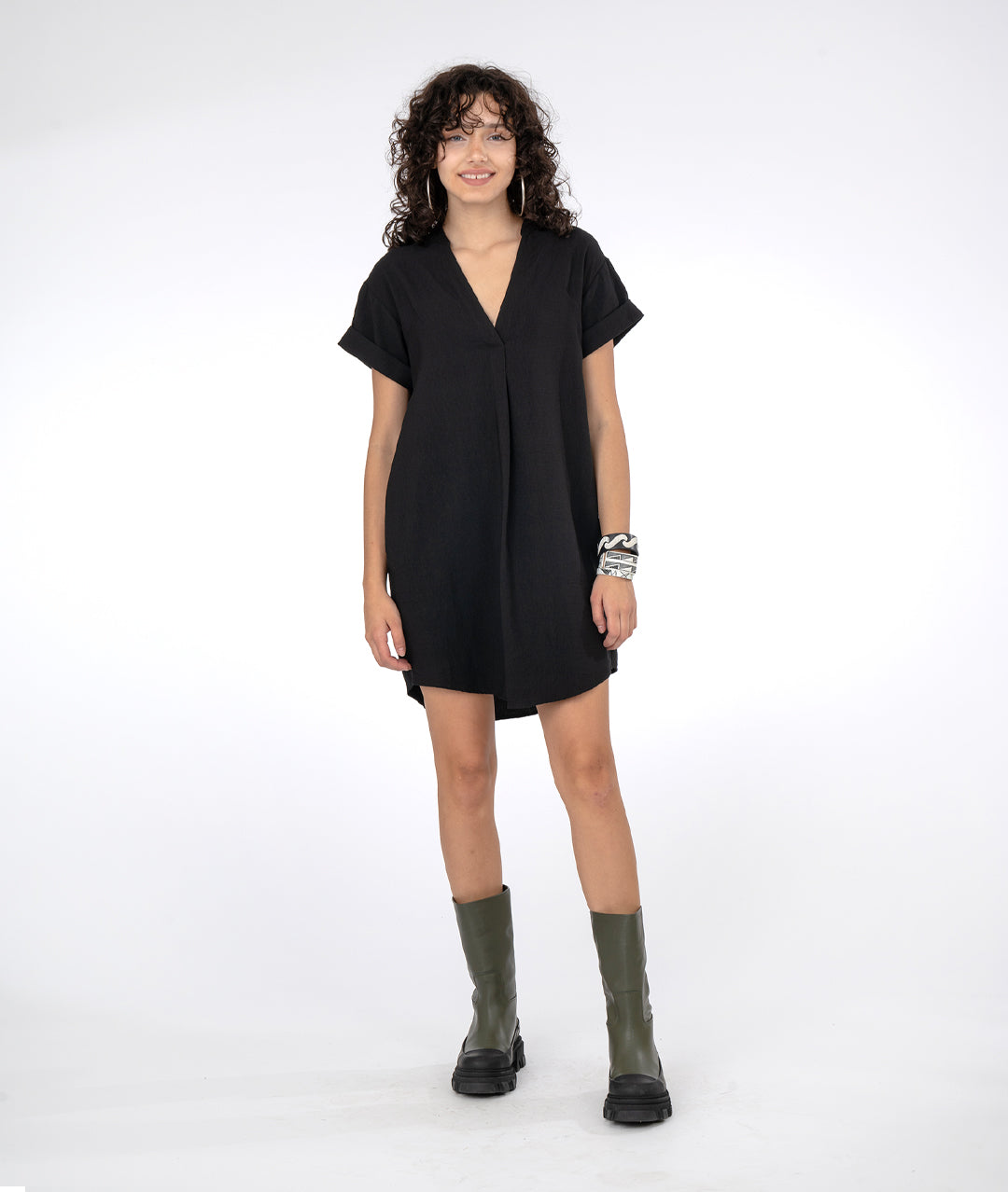 model in a boxy black dress with short cuffed sleeves and a vneck