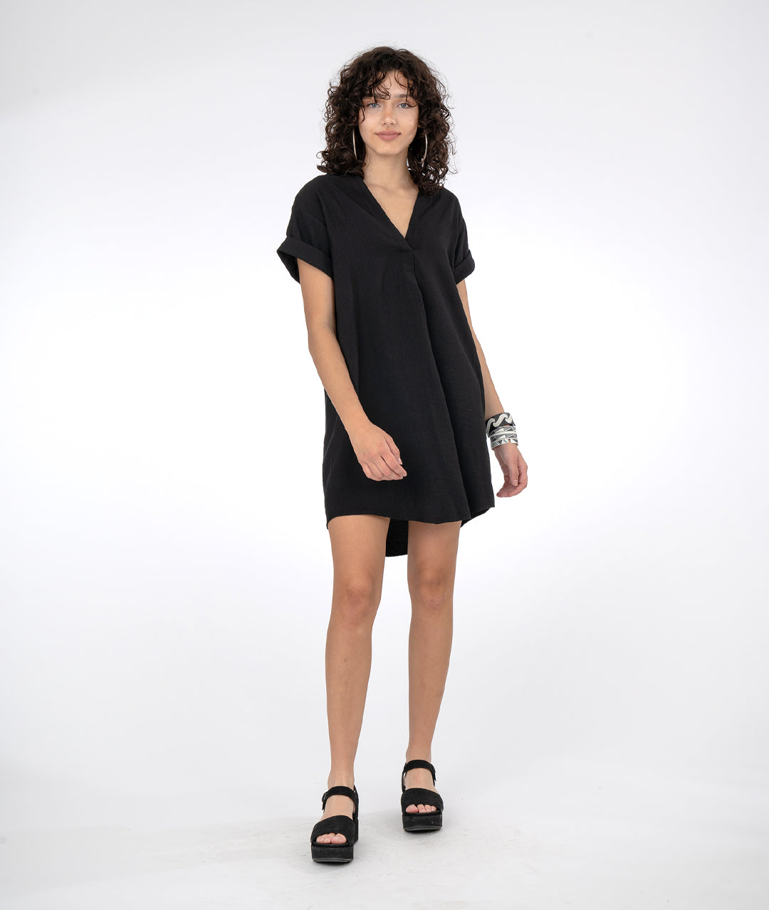 model in a boxy black dress with short cuffed sleeves and a vneck