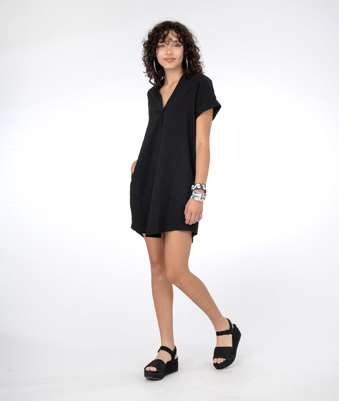 model in a boxy black dress with short cuffed sleeves and a vneck