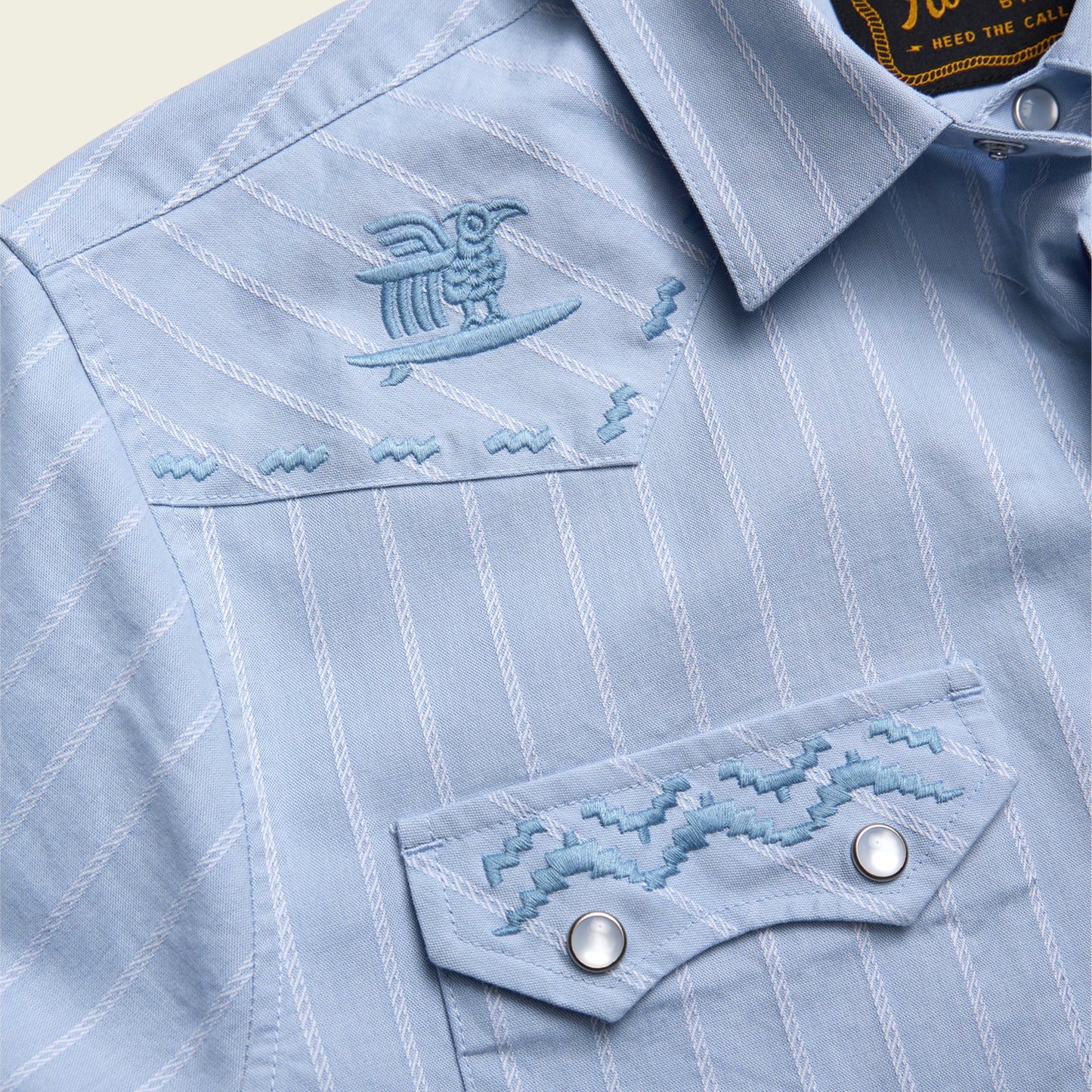 close up of embroidery on blue pearl snap short sleeve shirt with stripe pattern