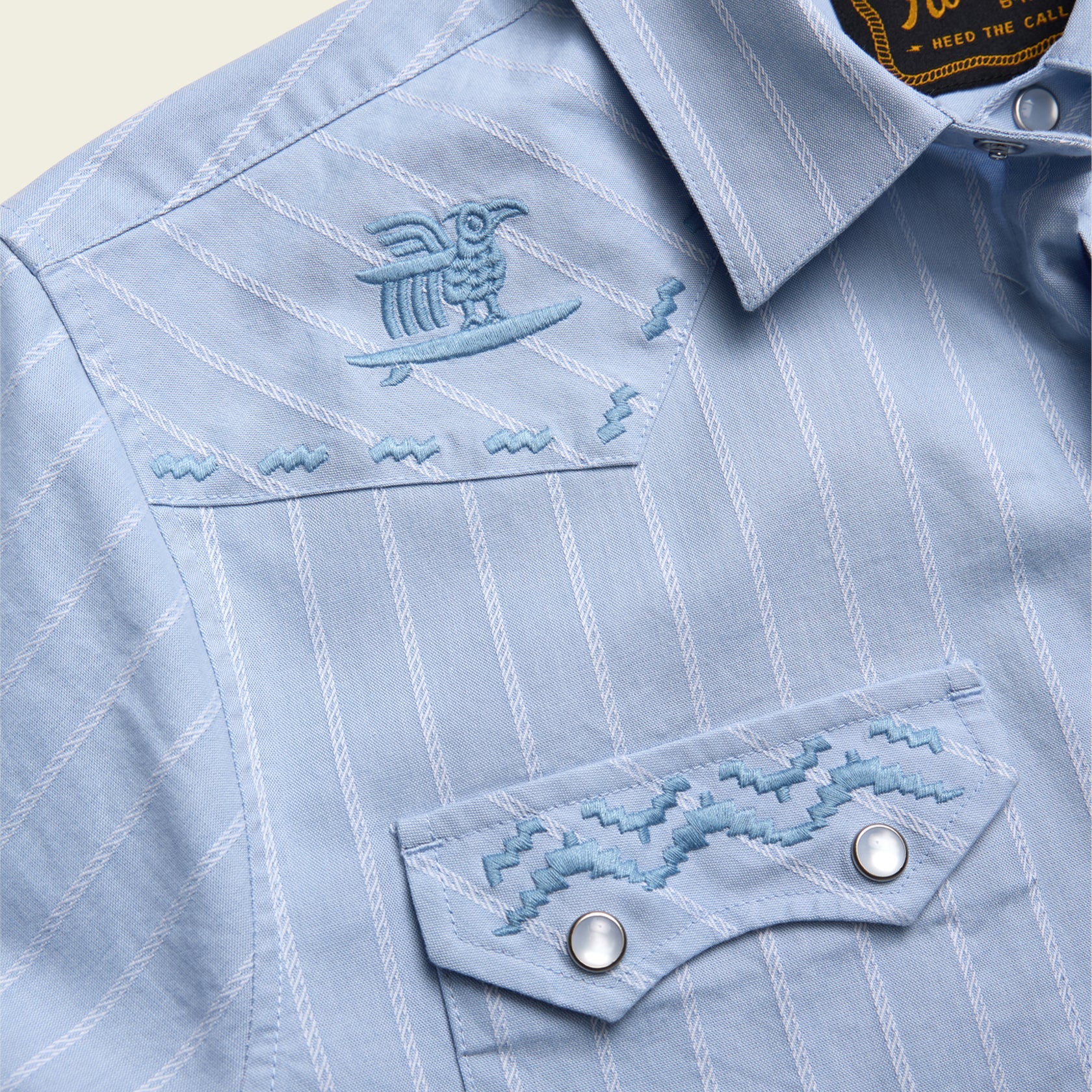 close up of embroidery on blue pearl snap short sleeve shirt with stripe pattern
