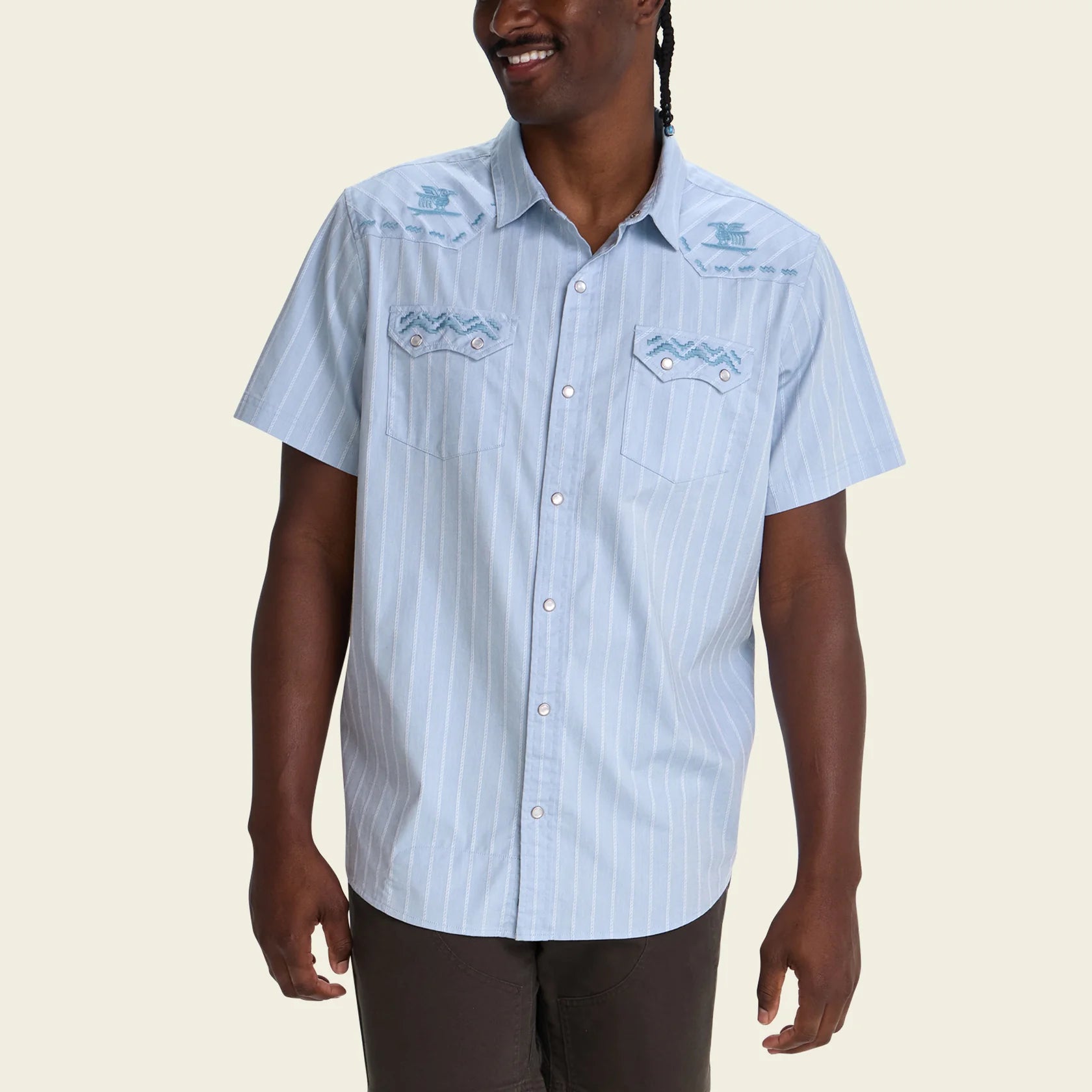 man wearing blue pearl snap short sleeve shirt with stripe pattern and embroidery on white background