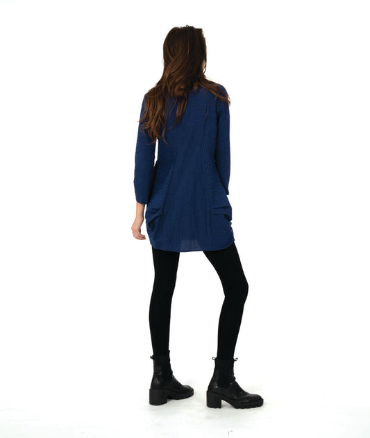 model in a blue and black striped tunic with long sleeves, a cowl neck, and princess seams. hip seams feature large shaping tucks
