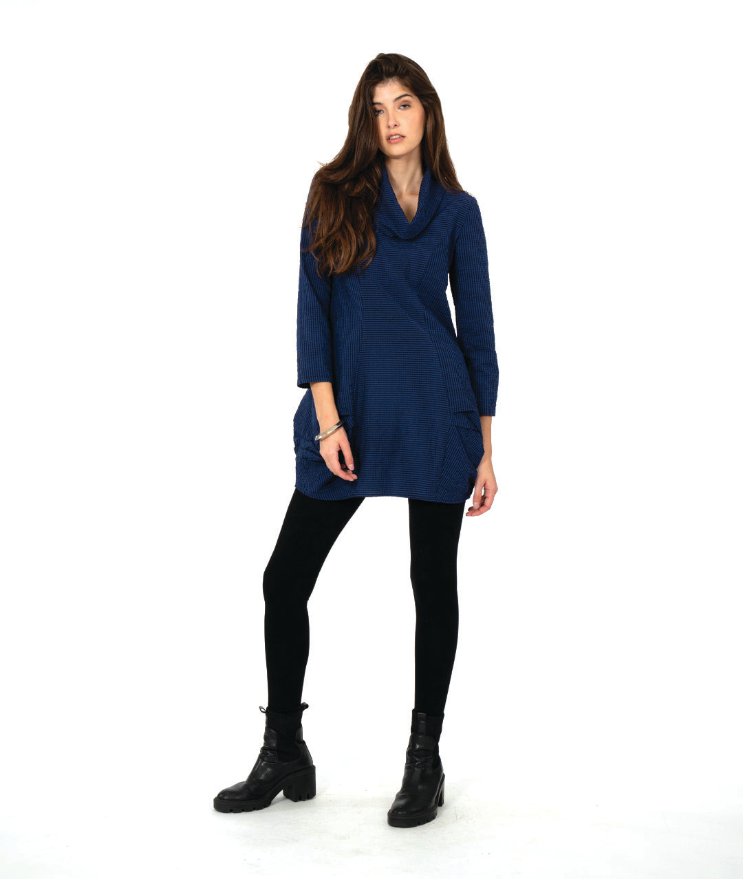 model in a blue and black striped tunic with long sleeves, a cowl neck, and princess seams. hip seams feature large shaping tucks