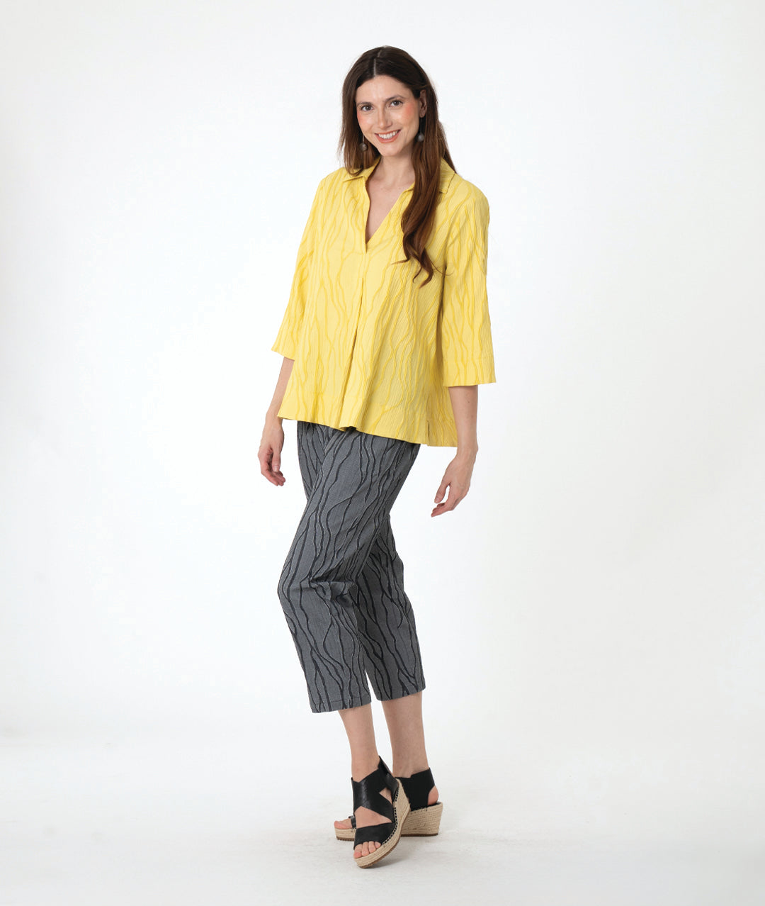 A woman modeling a grey wavy pattern crop pant with a matching yellow pullover top