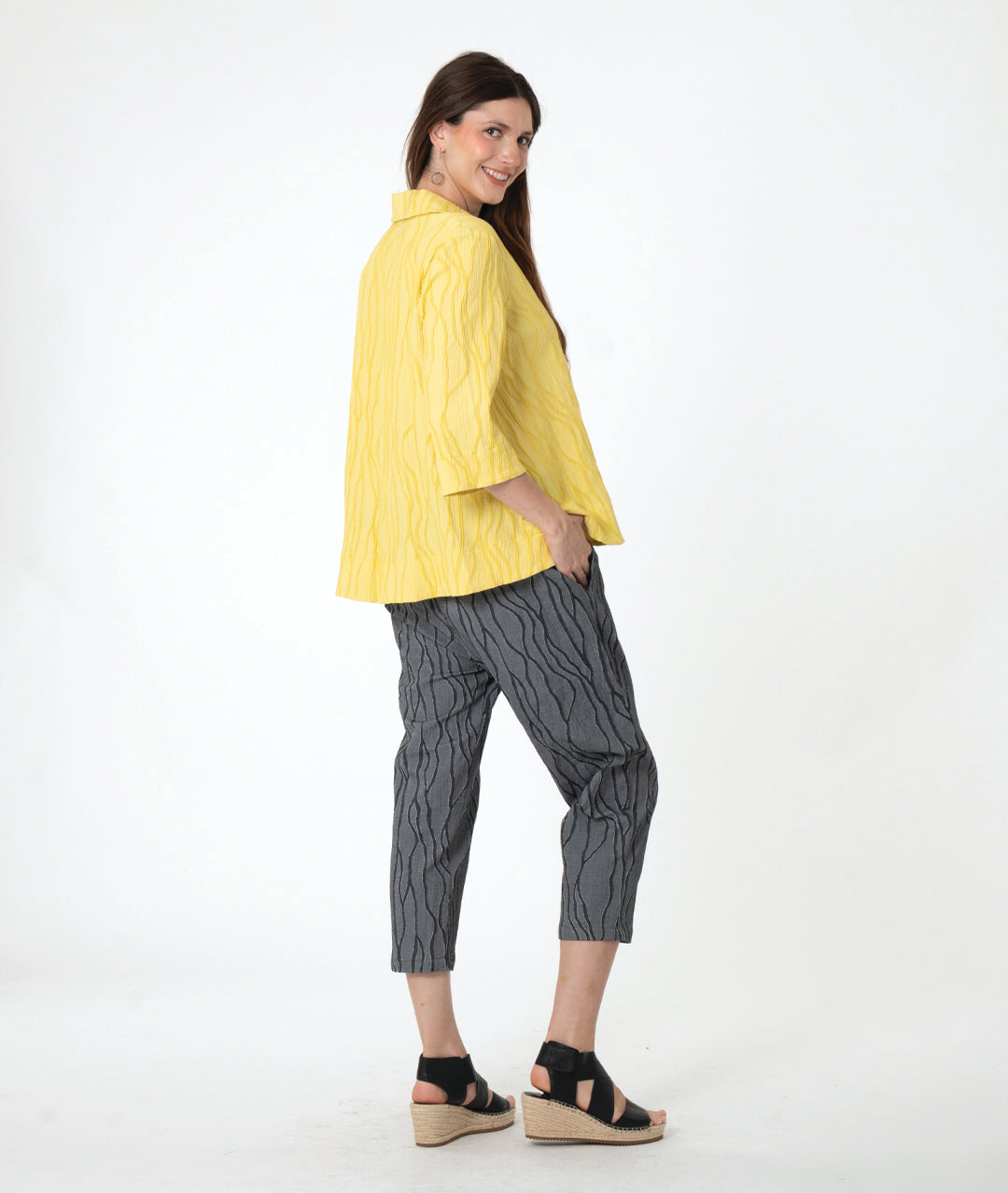 A woman modeling a grey wavy pattern crop pant with a matching yellow pullover top