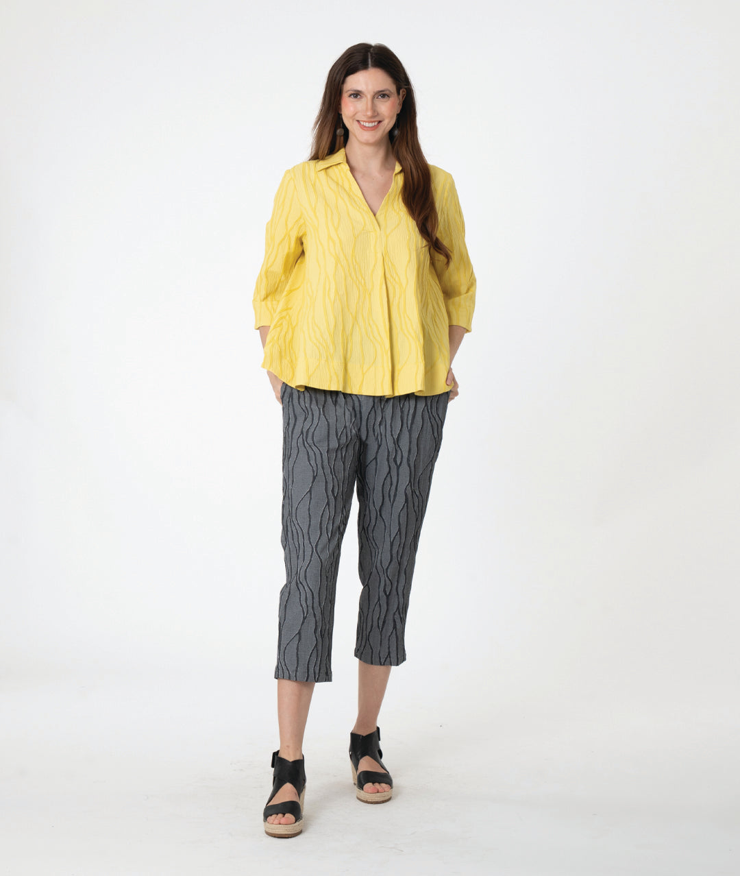 A woman modeling a grey wavy pattern crop pant with a matching yellow pullover top