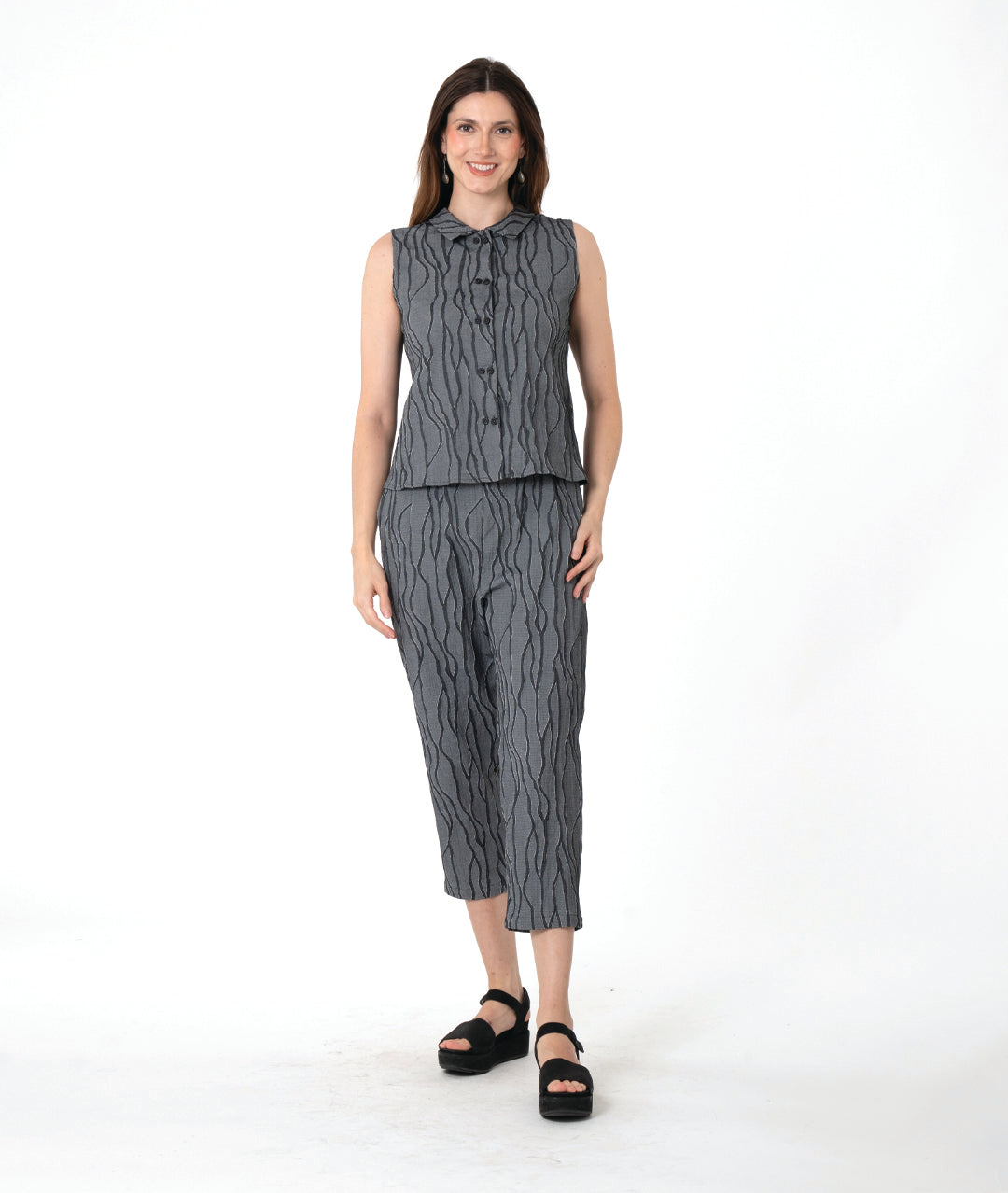 A woman modeling a matching sleeveless top and cropped pants set in a dark gray and black wavy pattern, paired with black platform sandals, against a plain white studio background.