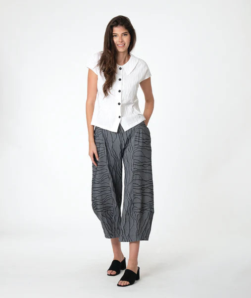 model wearing a white top and gray patterned pants on a white background