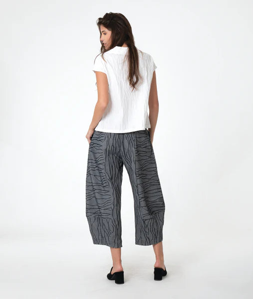 model wearing a white top and gray patterned pants on a white background