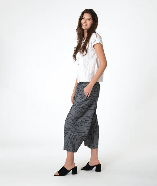 model wearing a white top and gray patterned pants on a white background