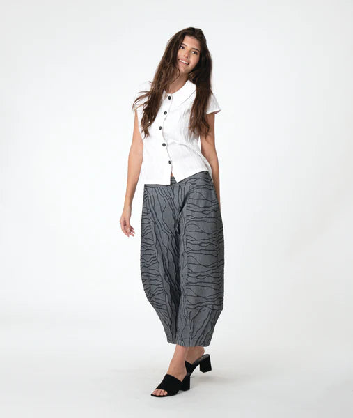 model wearing a white top and gray patterned pants on a white background
