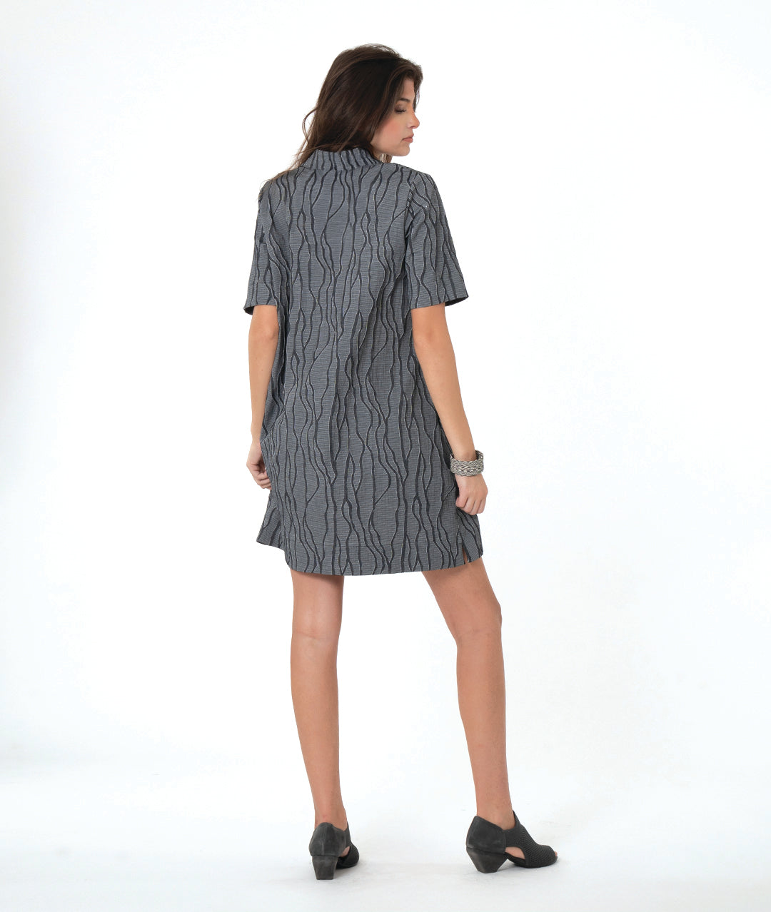 A woman modeling a dark gray wavy pattern pullover a line dress with an open collar, short sleeves and a knee length hem