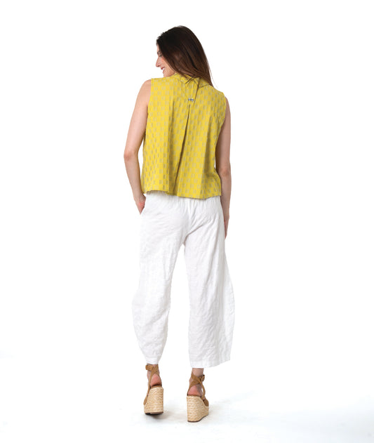 model in a yellow two toned sleeveless blouse, with a textured white pant with tucks below the knee 