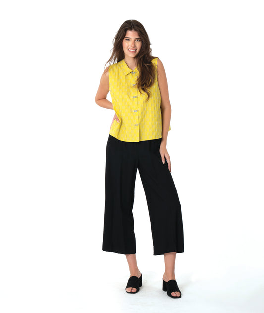 Woman wearing a yellow sleeveless button down blouse with a grey checkerboard print. worn with a black wide-leg pant.