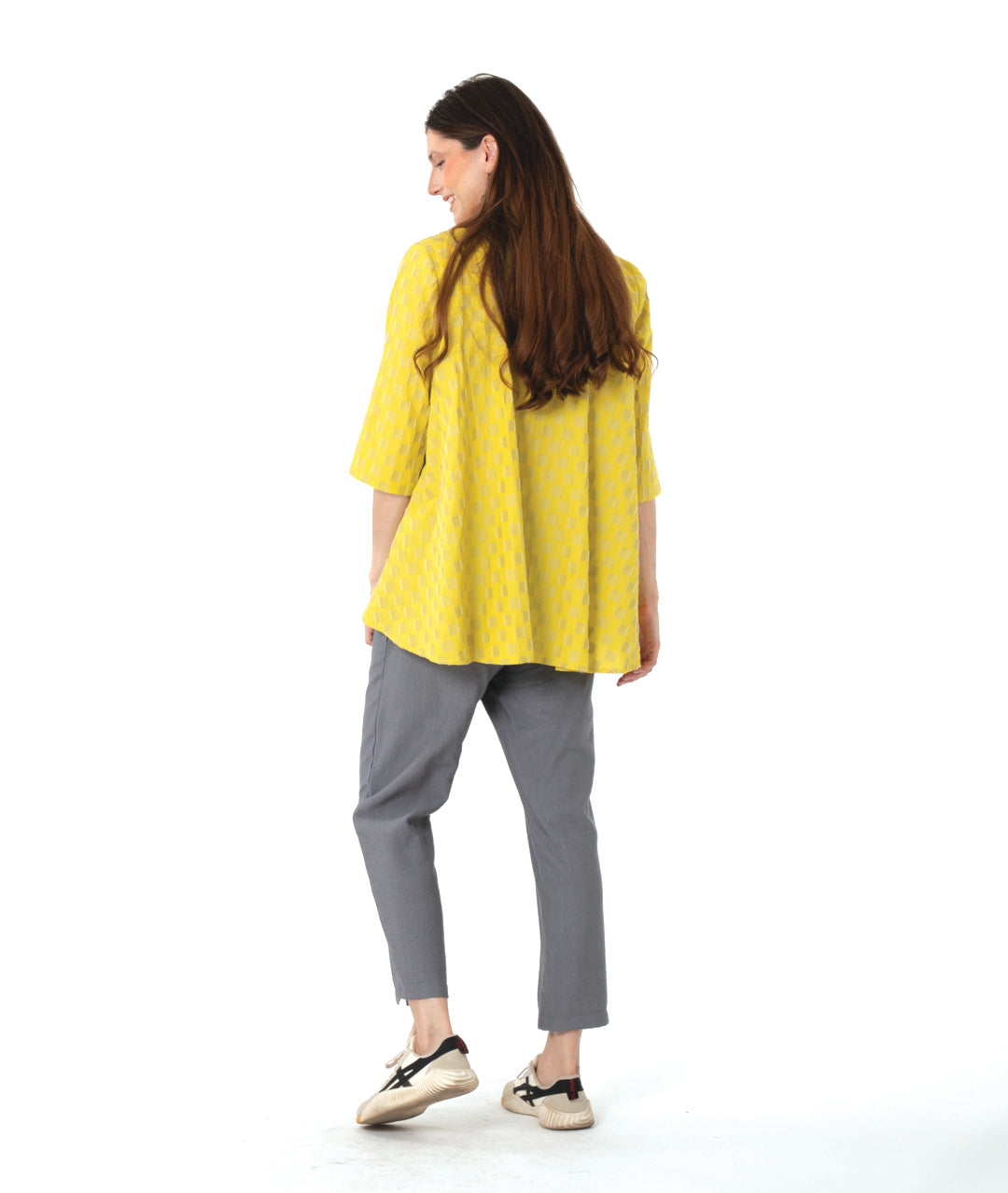 model in a yellow two tone checker board print button down blouse with 3/4 sleeves and a full body. worn with a slim grey pant