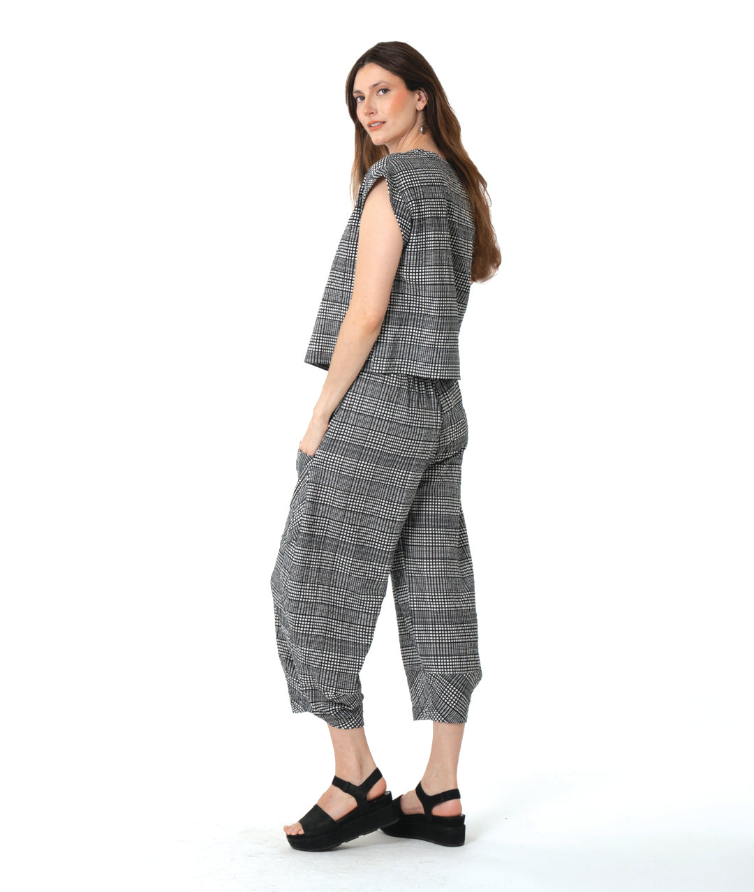 model in a black, white and grey plaid pair of pants with oversized contrasting pockets, wide legs and a tapered ankle. worn with a matching boxy pullover top