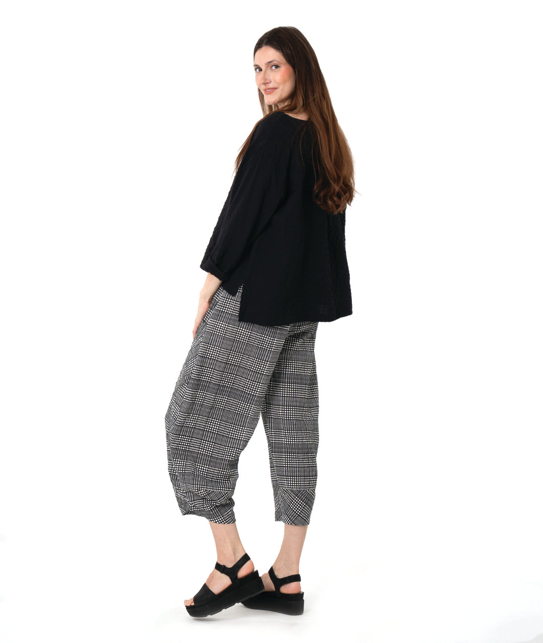 Woman wearing a black top and checkered pants on a white background