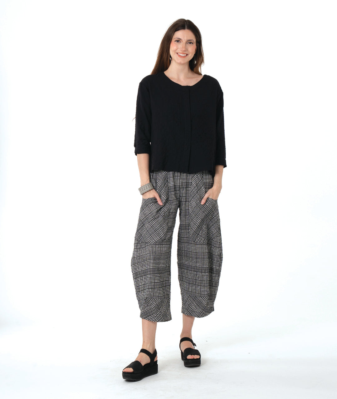 Woman wearing a black top and checkered pants on a white background