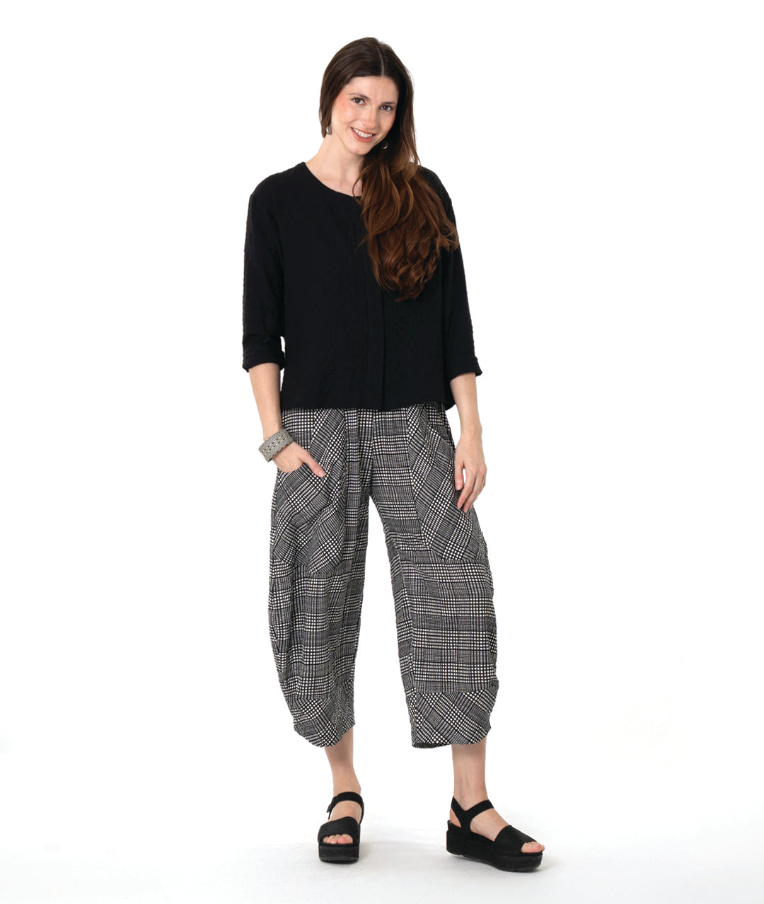 Woman wearing a black top and checkered pants on a white background