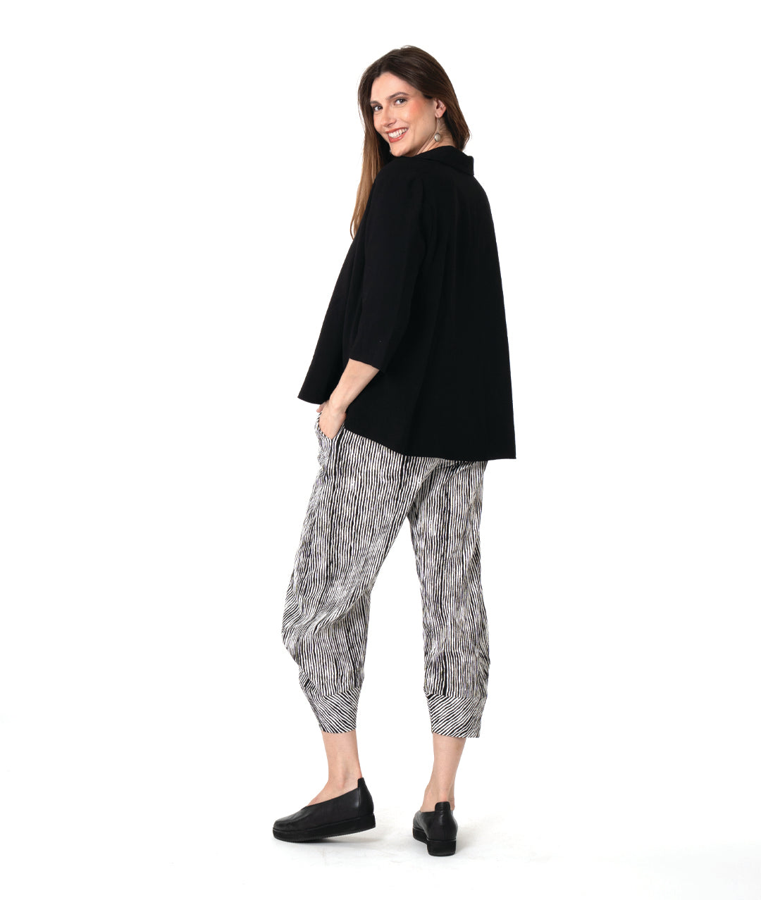 model in a wide leg black and white striped pant with a tapered ankle, worn with a black pullover blouse with 3/4 sleeves, side splits, a v-neck and open collar