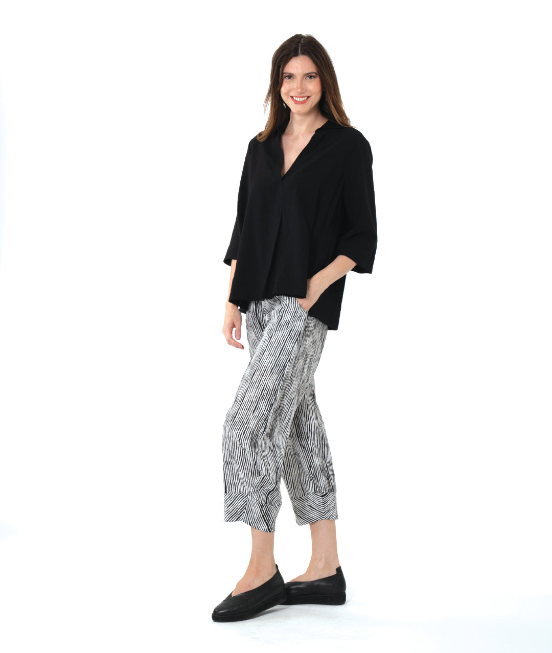 model in a wide leg black and white striped pant with a tapered ankle, worn with a black pullover blouse with 3/4 sleeves, side splits, a v-neck and open collar