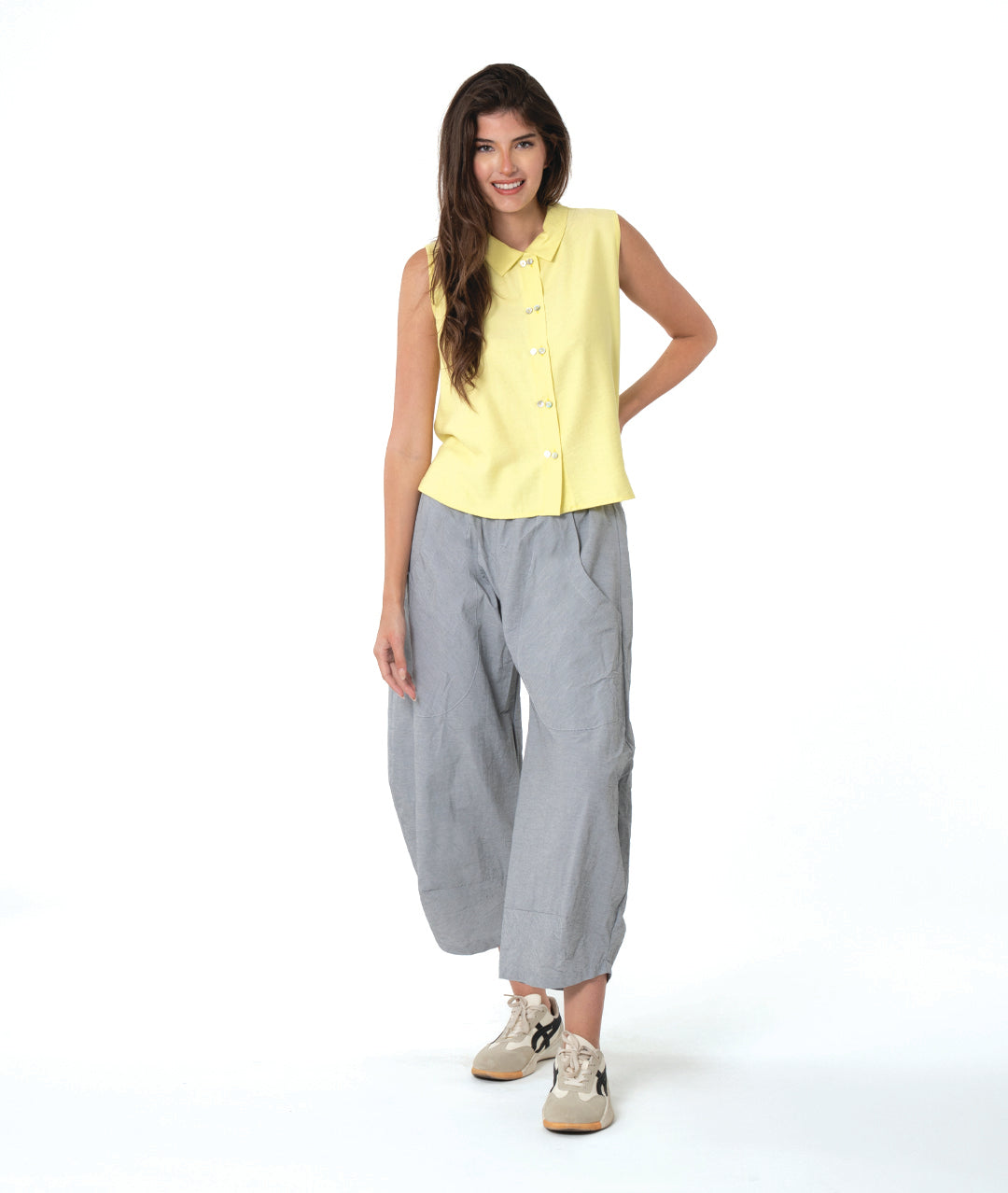 model in a wide leg grey and white striped pant with a tapered ankle, worn with a soft yellow sleeveless button down blouse with a twin button detail