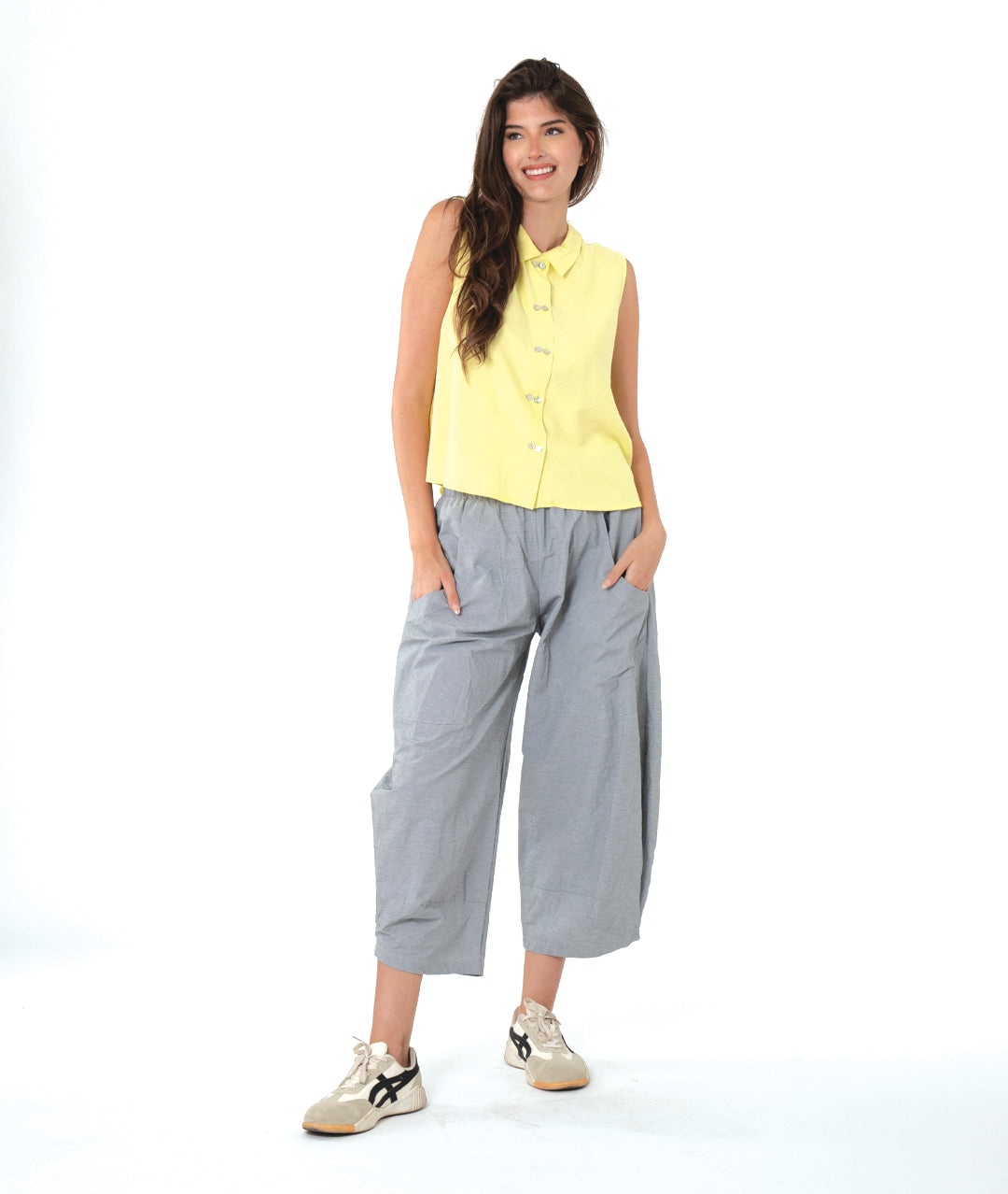 model in a wide leg grey and white striped pant with a tapered ankle, worn with a soft yellow sleeveless button down blouse with a twin button detail