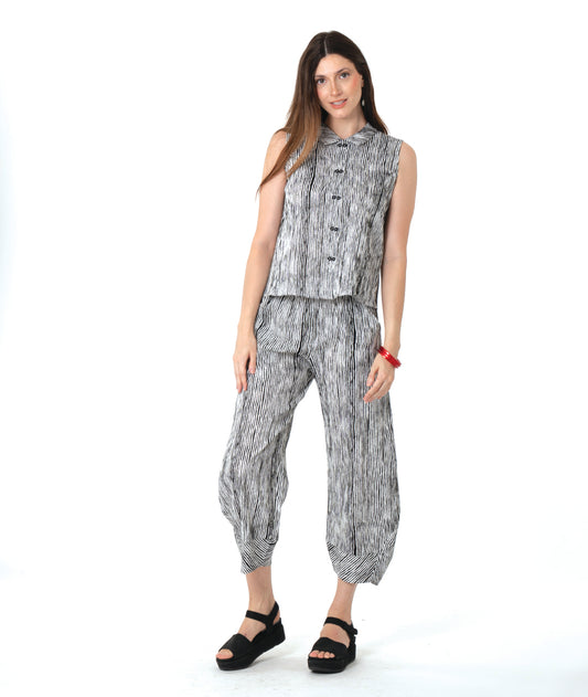 model in a wide leg black and white striped pant with a tapered ankle, worn with a matching sleeveless button down blouse