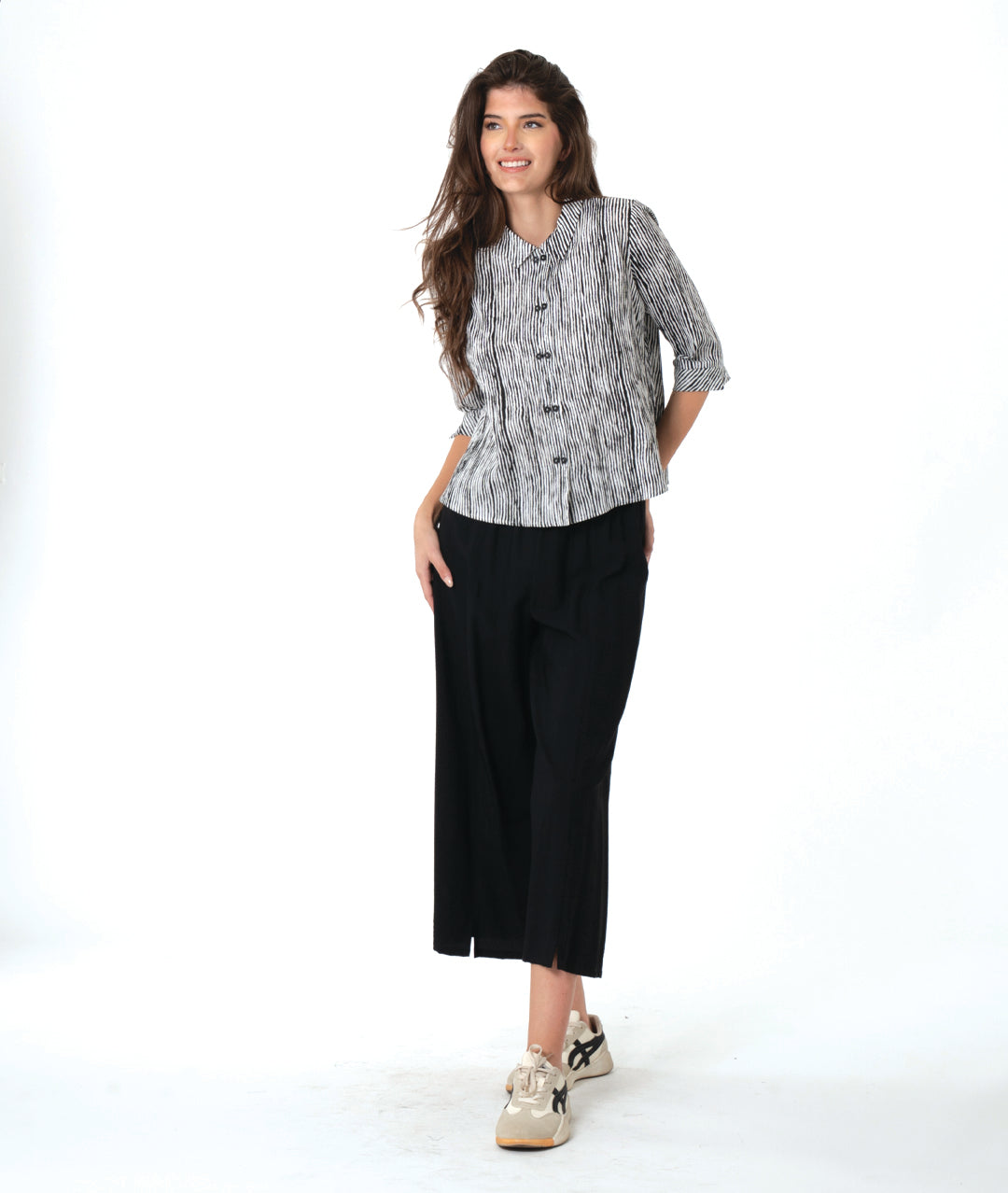 model in a wide leg black pant with a split at the ankle front, worn with a black and white striped blouse with 3/4 sleeves and a twin button detail
